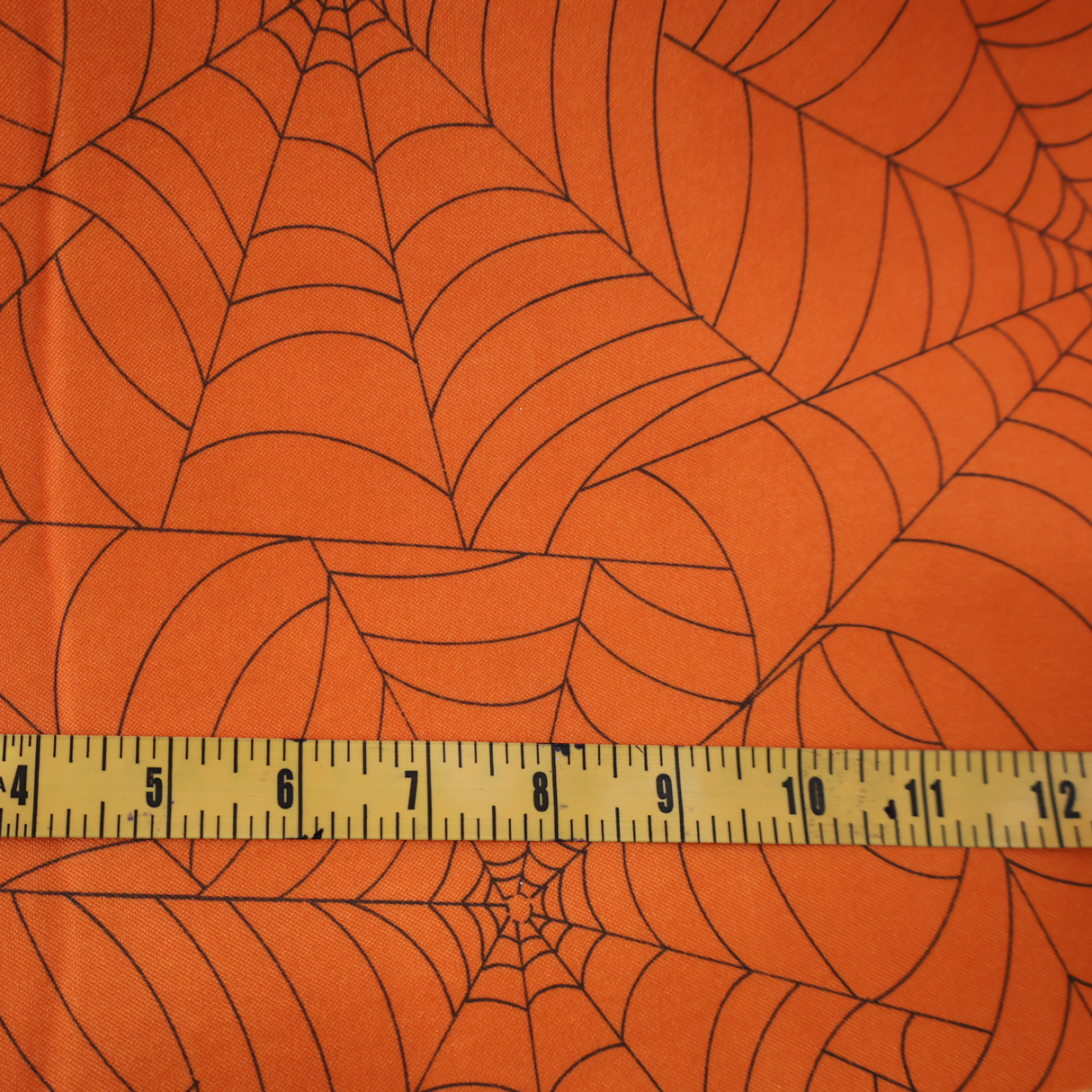 Halloween projects with this orange spider web fabric By Yard